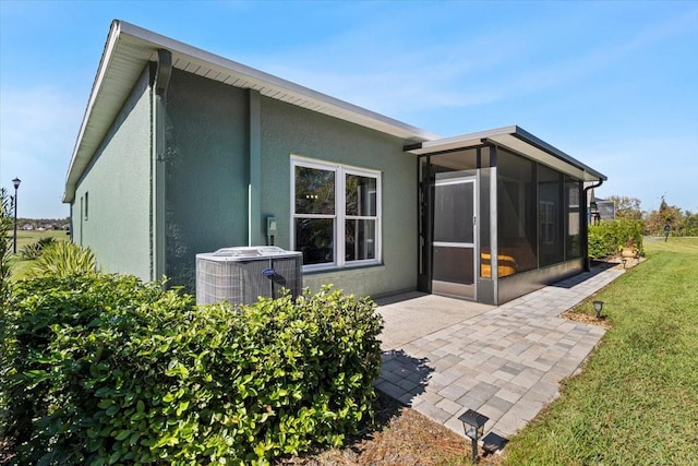 back of house with a yard, a sunroom, a patio area, and central air condition unit