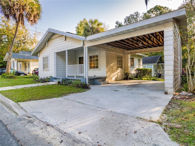 ranch-style home featuring a front lawn, covered porch, and a carport