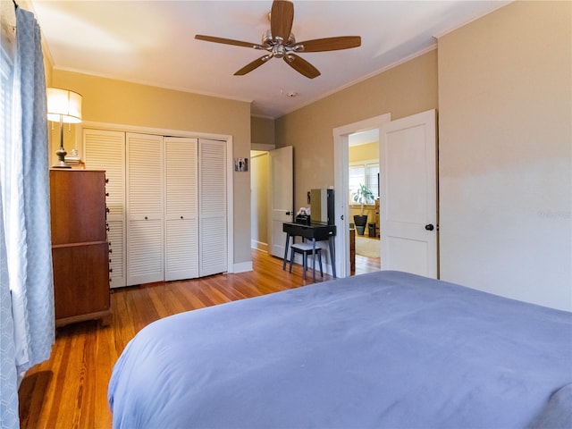 bedroom with hardwood / wood-style flooring, ceiling fan, crown molding, and a closet