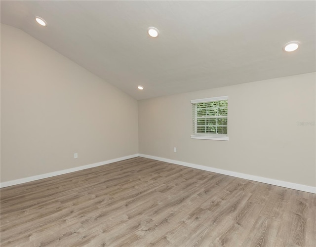 unfurnished room featuring light hardwood / wood-style flooring and lofted ceiling