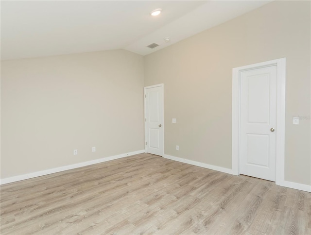 empty room featuring baseboards, lofted ceiling, visible vents, and light wood-style floors