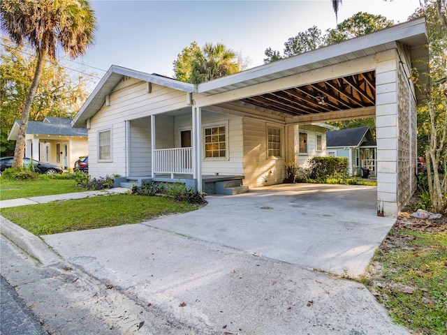 ranch-style home with concrete driveway, a porch, a front yard, and a carport