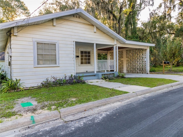 view of front of property with concrete driveway, a porch, and a front yard