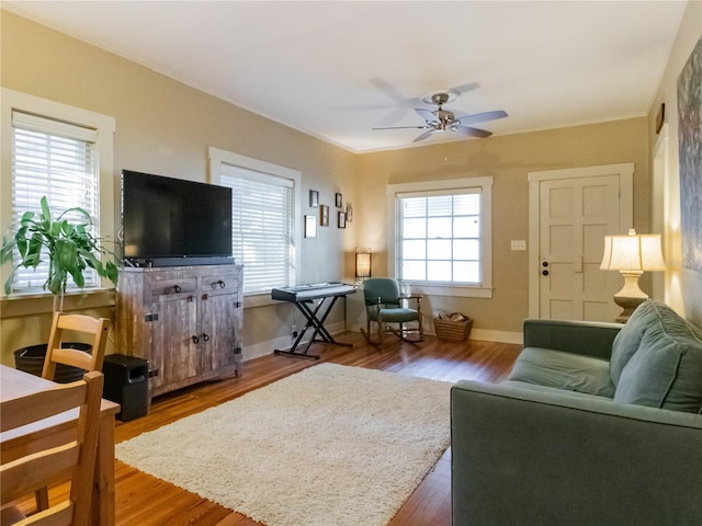 living area with a healthy amount of sunlight, ceiling fan, and wood finished floors