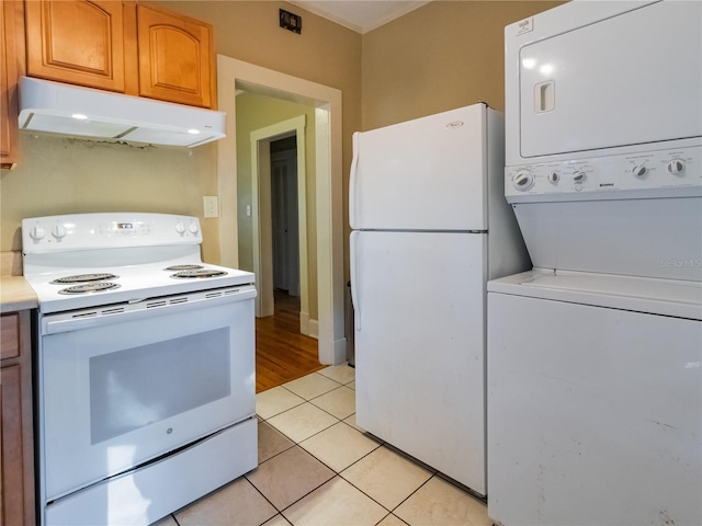kitchen with light countertops, stacked washer / drying machine, under cabinet range hood, light tile patterned floors, and white appliances