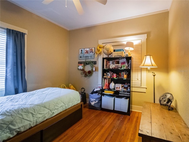 bedroom featuring a ceiling fan, ornamental molding, and wood finished floors