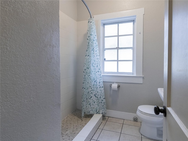 bathroom with baseboards, toilet, a stall shower, and tile patterned floors