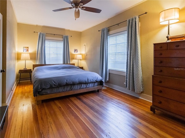 bedroom featuring hardwood / wood-style floors, baseboards, and multiple windows