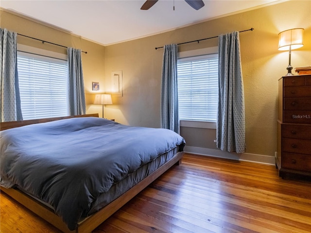 bedroom featuring baseboards, ceiling fan, ornamental molding, and hardwood / wood-style flooring