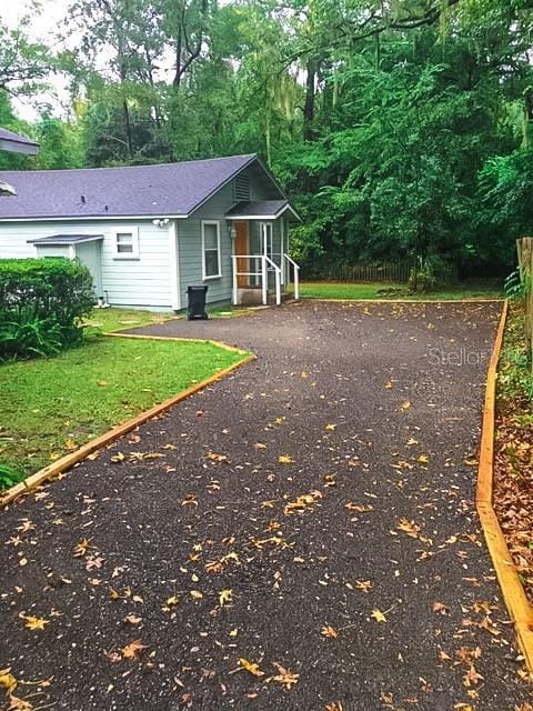 exterior space featuring roof with shingles and fence