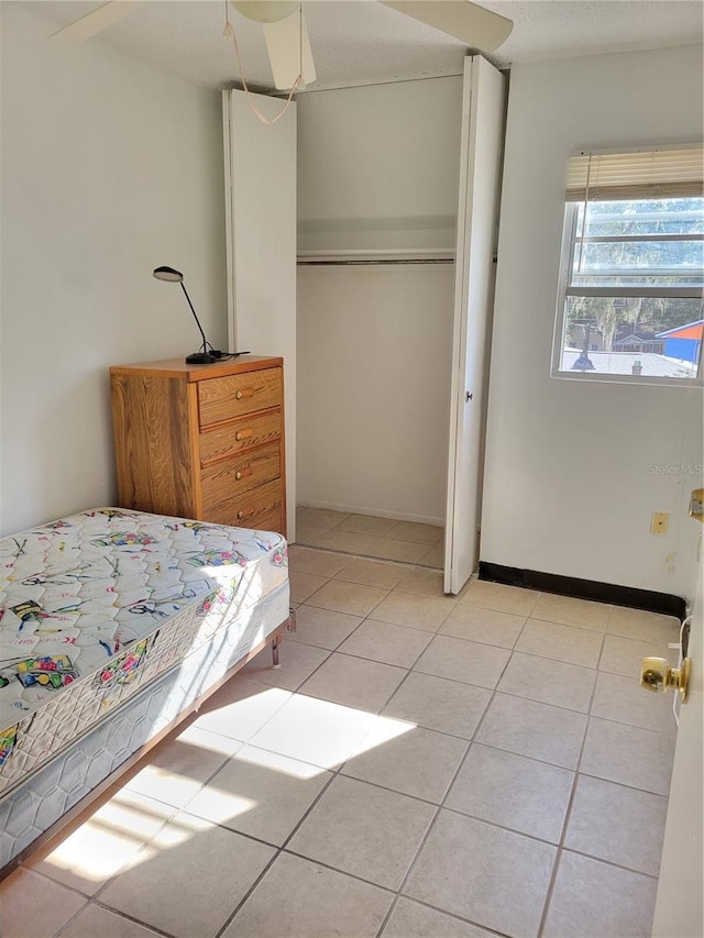 bedroom featuring light tile patterned floors, a closet, and baseboards