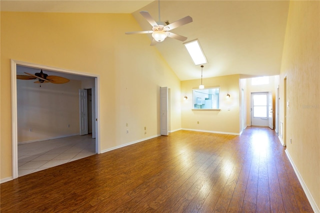 unfurnished living room with ceiling fan, a skylight, high vaulted ceiling, and light hardwood / wood-style flooring