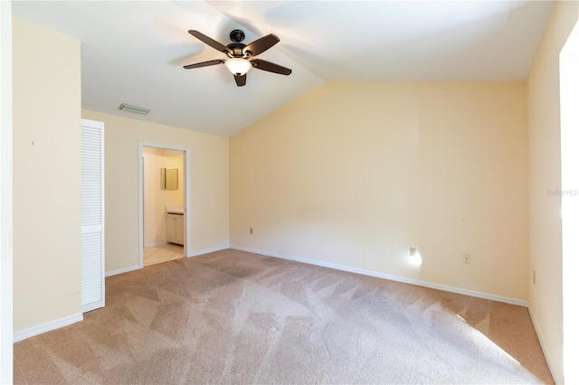 unfurnished bedroom featuring ceiling fan, light colored carpet, ensuite bathroom, and lofted ceiling