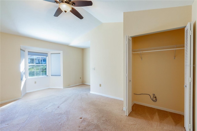 unfurnished bedroom with ceiling fan, a closet, light colored carpet, and vaulted ceiling