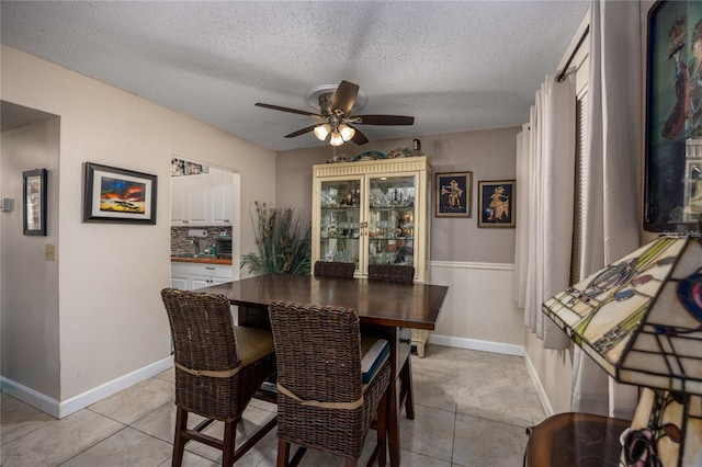 tiled dining room with ceiling fan and a textured ceiling