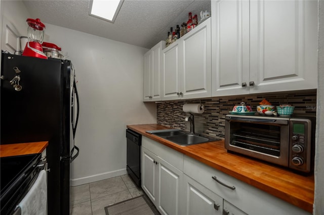 kitchen featuring white cabinets, black appliances, sink, decorative backsplash, and butcher block counters