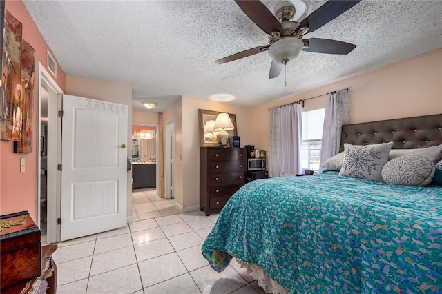 tiled bedroom with ceiling fan, a textured ceiling, and ensuite bath