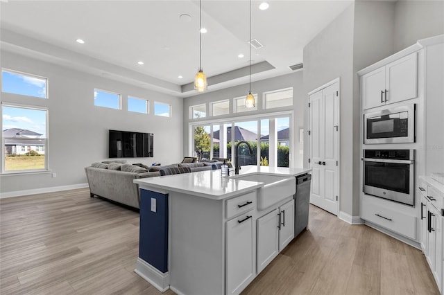 kitchen with a healthy amount of sunlight, white cabinetry, a kitchen island with sink, and appliances with stainless steel finishes