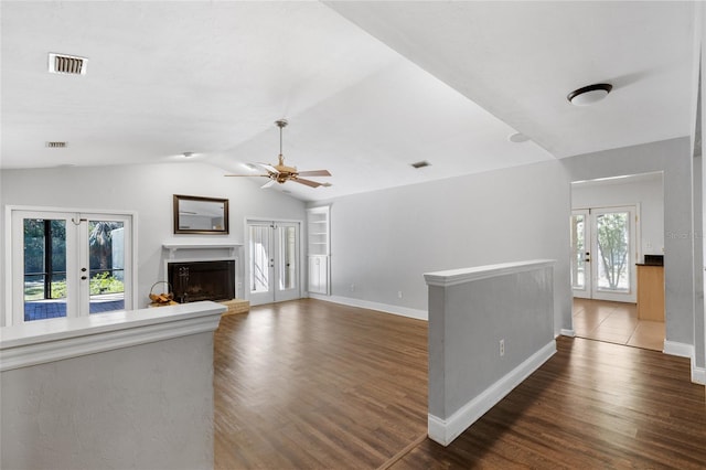 unfurnished living room with french doors, plenty of natural light, and dark wood-type flooring