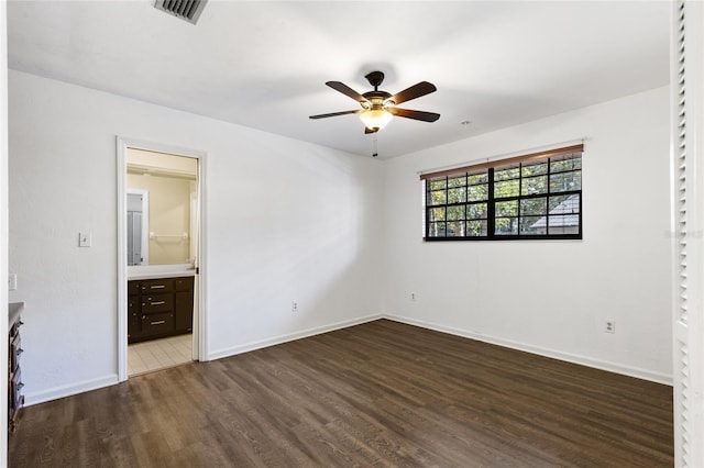 unfurnished bedroom featuring dark hardwood / wood-style floors, ceiling fan, and ensuite bathroom