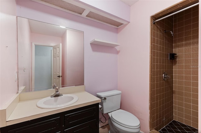 bathroom with vanity, toilet, and a tile shower