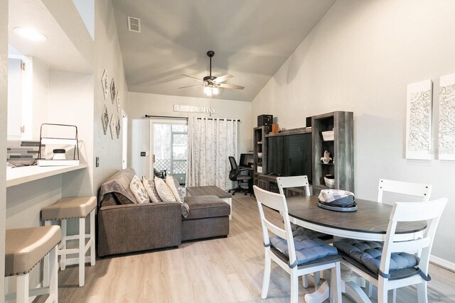 dining room featuring light wood-type flooring, high vaulted ceiling, and ceiling fan