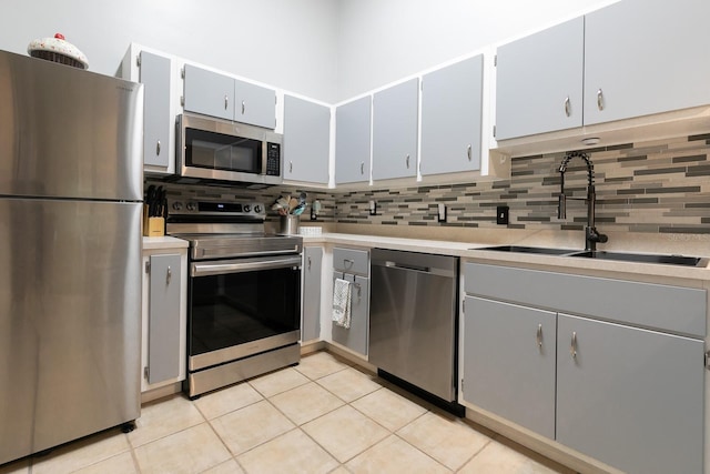 kitchen with decorative backsplash, sink, light tile patterned flooring, and appliances with stainless steel finishes