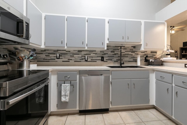 kitchen featuring sink, decorative backsplash, ceiling fan, light tile patterned floors, and stainless steel appliances