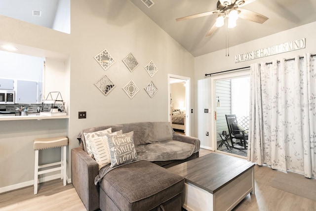 living room with ceiling fan, light hardwood / wood-style floors, and high vaulted ceiling