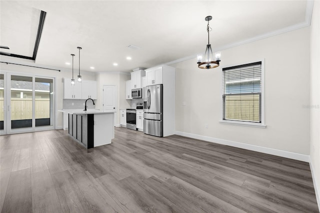 kitchen with pendant lighting, white cabinets, a center island with sink, and stainless steel appliances