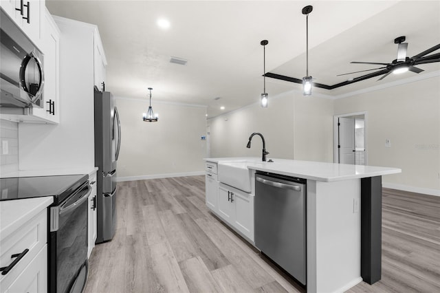 kitchen with appliances with stainless steel finishes, ceiling fan, sink, white cabinets, and an island with sink