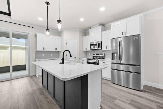 kitchen featuring appliances with stainless steel finishes, light wood-type flooring, tasteful backsplash, white cabinets, and hanging light fixtures