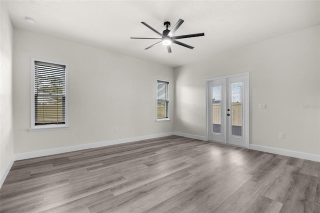 empty room featuring ceiling fan, light wood-type flooring, and french doors