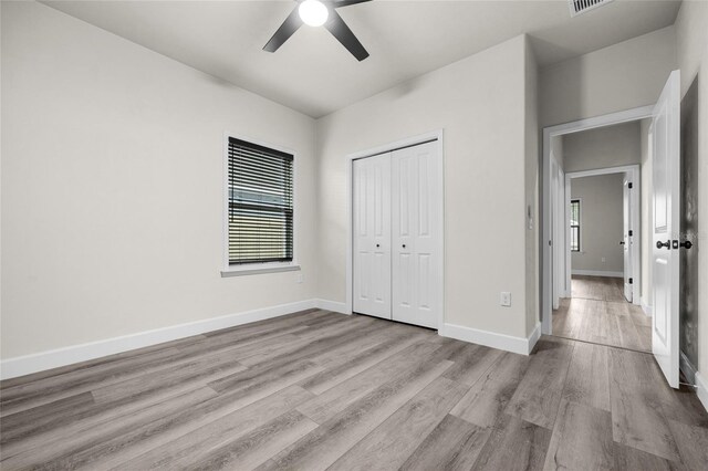 unfurnished bedroom featuring ceiling fan, light hardwood / wood-style floors, and a closet