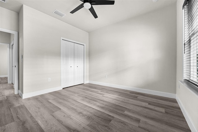 unfurnished bedroom featuring hardwood / wood-style floors, ceiling fan, and a closet