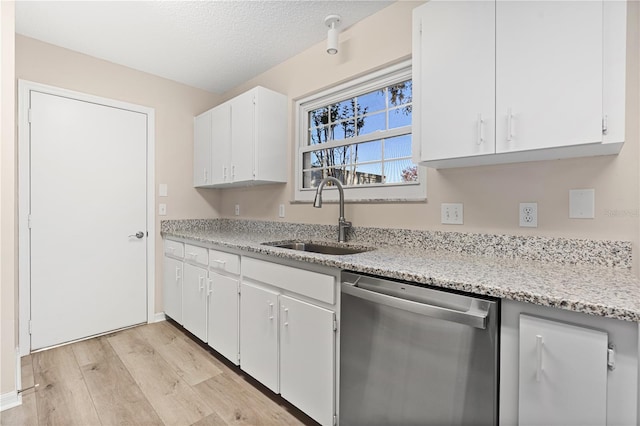 kitchen featuring white cabinets, sink, light hardwood / wood-style flooring, stainless steel dishwasher, and a textured ceiling