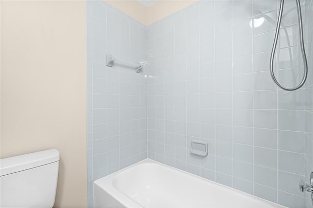 bathroom with tiled shower / bath combo and toilet