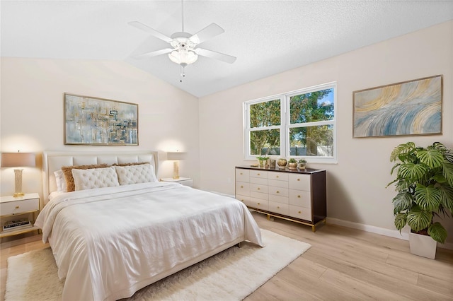 bedroom with a textured ceiling, light wood-type flooring, vaulted ceiling, and ceiling fan