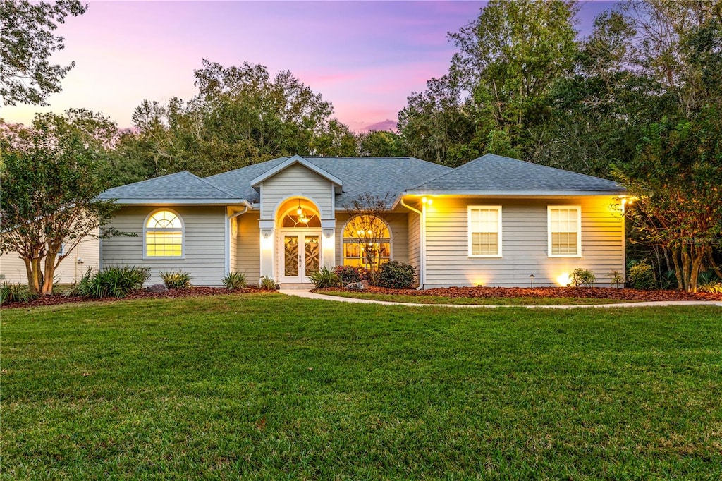 ranch-style home featuring french doors and a yard