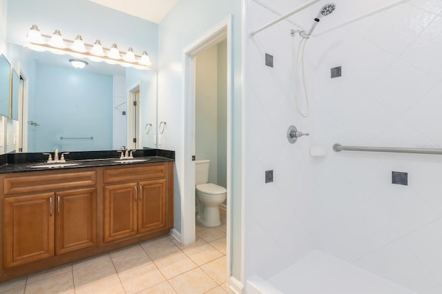 bathroom with tile patterned floors, vanity, a tile shower, and toilet