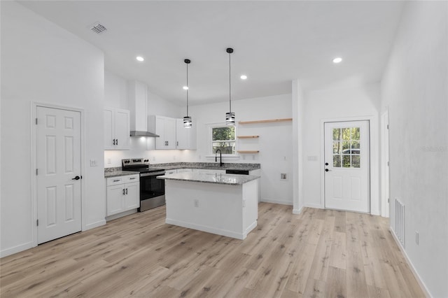 kitchen with electric stove, white cabinetry, a center island, and light hardwood / wood-style flooring