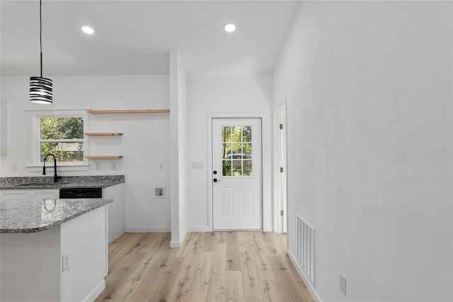 kitchen featuring a wealth of natural light, light hardwood / wood-style flooring, hanging light fixtures, and sink