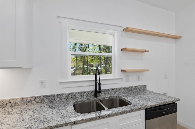 kitchen featuring light stone counters, dishwasher, white cabinets, and sink