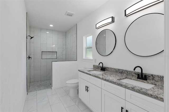 bathroom with a tile shower, vanity, and toilet