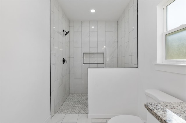 bathroom with tiled shower, vanity, and toilet