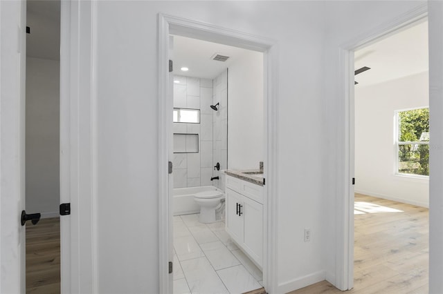 full bathroom featuring vanity, toilet, wood-type flooring, and tiled shower / bath combo