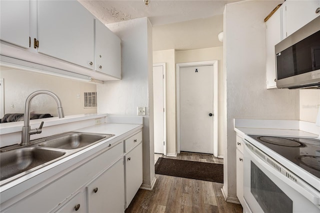 4000 SW 23rd St Unit 5-207, Gainesville, FL 32608 - kitchen with stainless steel microwave, white range with electric cooktop, dark wood-style floors, light countertops, and white cabinetry