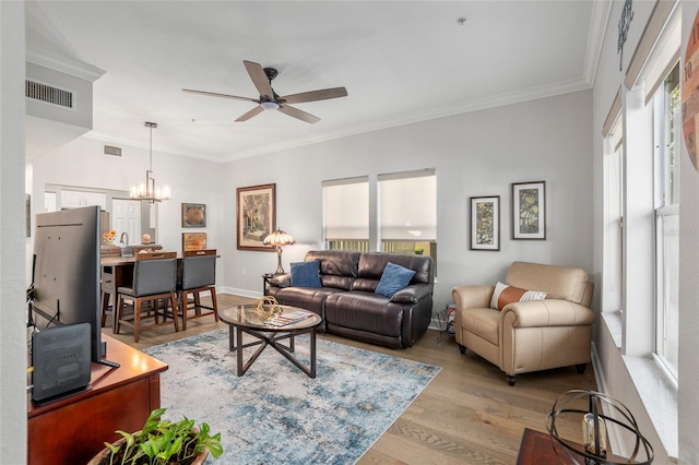 living room featuring ceiling fan with notable chandelier, light hardwood / wood-style floors, and crown molding