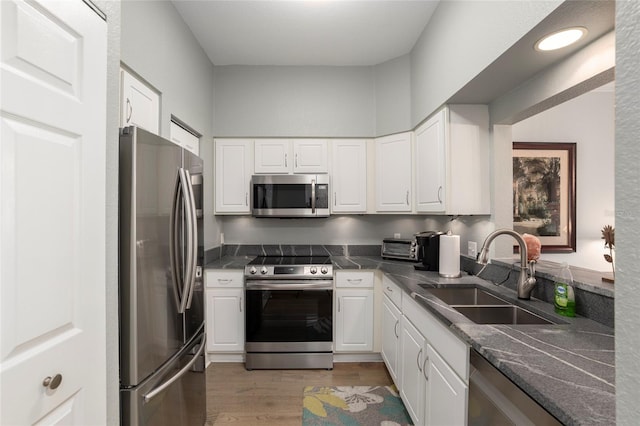 kitchen with sink, white cabinets, stainless steel appliances, and light wood-type flooring