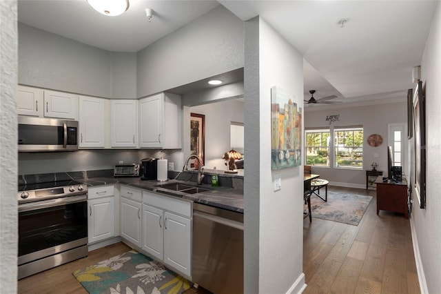 kitchen with light wood-type flooring, stainless steel appliances, white cabinetry, and sink